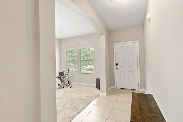 117 Mission Cove Cir, Saint Augustine, FL 32084 - foyer with arched walkways, light colored carpet, light tile patterned flooring, baseboards, and a textured ceiling
