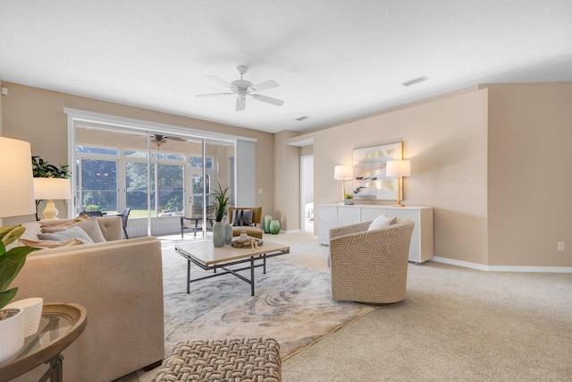 living room with a textured ceiling, light colored carpet, and ceiling fan