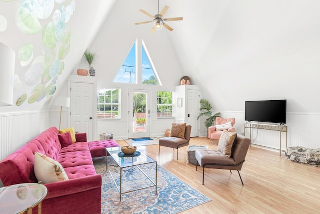 living room with a wainscoted wall, high vaulted ceiling, wood finished floors, and a ceiling fan