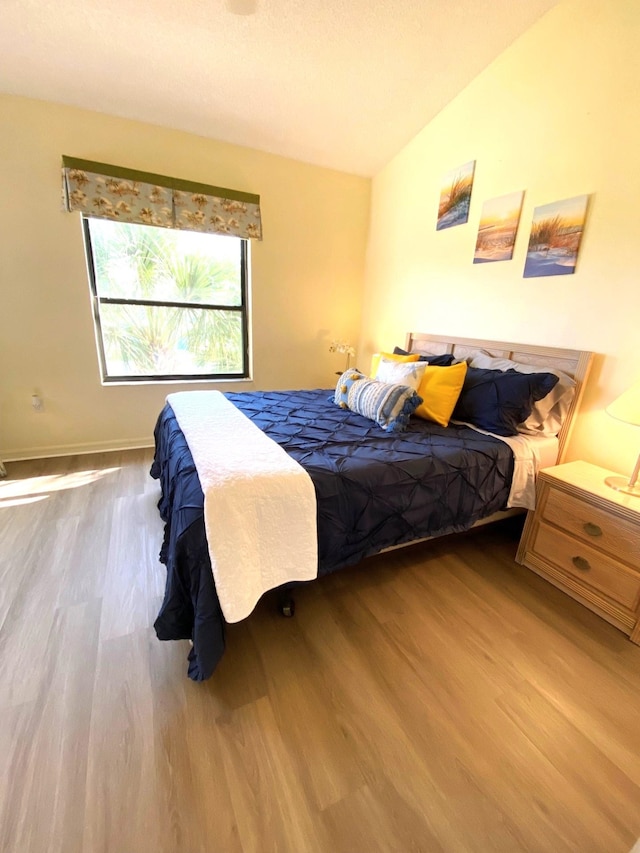 bedroom with light hardwood / wood-style floors and lofted ceiling