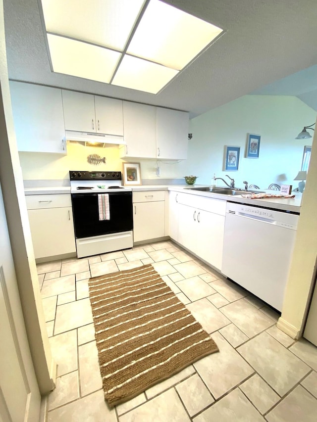 kitchen featuring kitchen peninsula, white appliances, sink, light tile patterned floors, and white cabinets