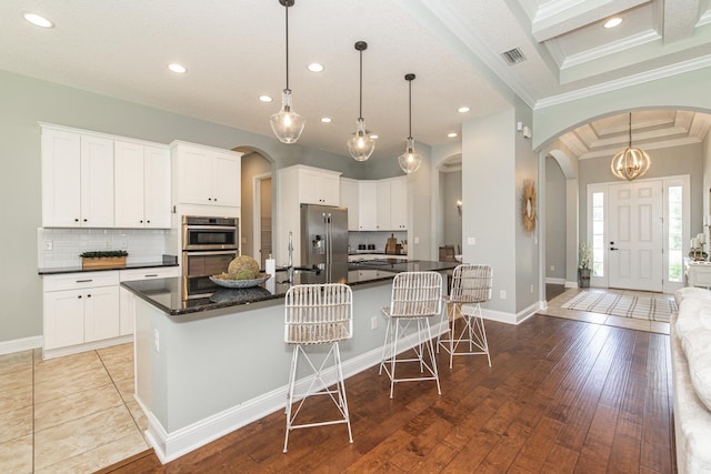 kitchen featuring white cabinets, decorative light fixtures, light hardwood / wood-style floors, and a kitchen island with sink