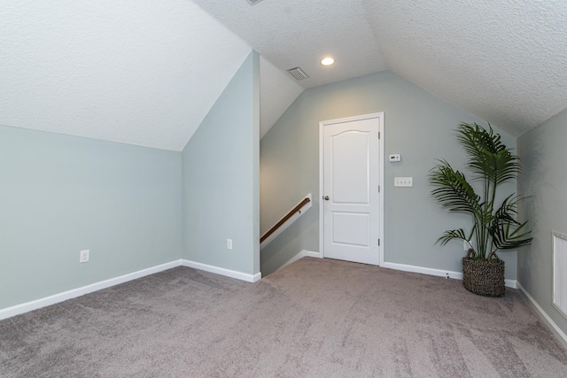 bonus room with light colored carpet, a textured ceiling, and vaulted ceiling