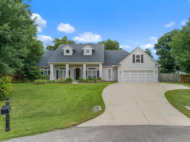 view of front of home with covered porch, a front yard, and a garage