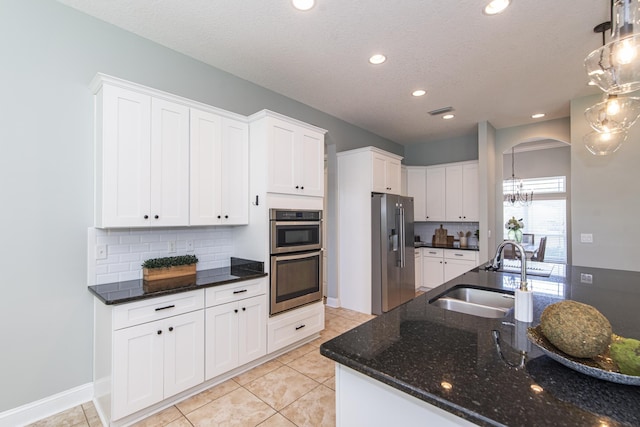 kitchen with backsplash, stainless steel appliances, sink, decorative light fixtures, and white cabinets