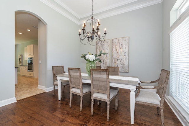 dining space featuring wood-type flooring, crown molding, and a chandelier