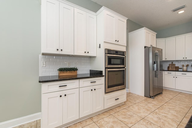 kitchen with white cabinets, appliances with stainless steel finishes, a textured ceiling, and tasteful backsplash