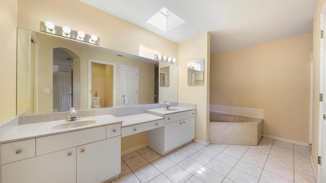 bathroom featuring a bath, a skylight, vanity, baseboards, and toilet