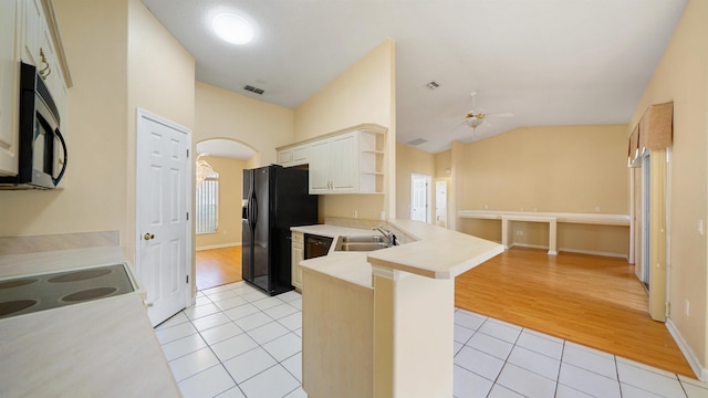 kitchen featuring visible vents, a peninsula, black refrigerator with ice dispenser, stainless steel microwave, and light tile patterned floors