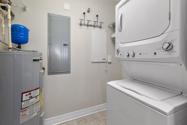 laundry area with baseboards, laundry area, electric panel, water heater, and stacked washer / dryer