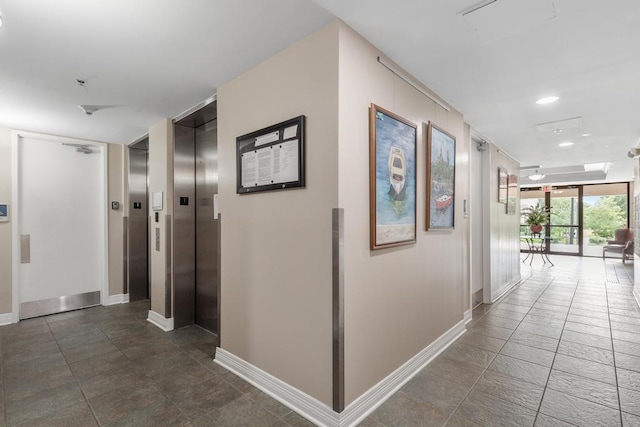 hallway featuring elevator, recessed lighting, a wall of windows, and baseboards