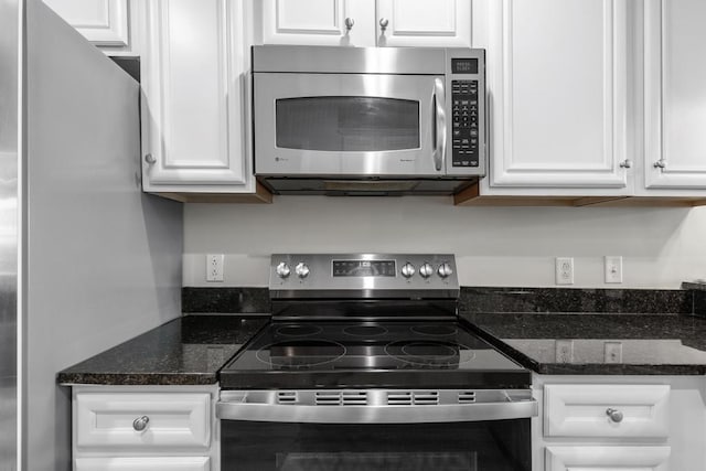 kitchen with stainless steel appliances, white cabinets, and dark stone counters