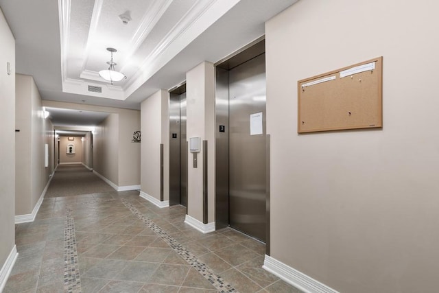 corridor featuring elevator, baseboards, crown molding, and a tray ceiling