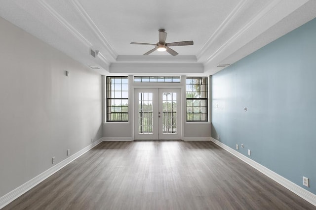 empty room with wood finished floors, a ceiling fan, a tray ceiling, french doors, and crown molding