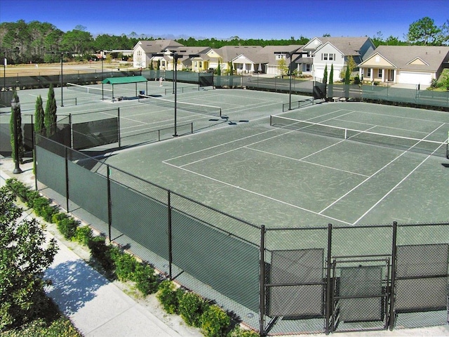 view of tennis court with a gate, a residential view, and fence