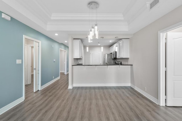 kitchen with a tray ceiling, baseboards, dark countertops, and freestanding refrigerator