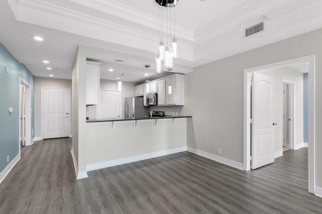 kitchen featuring dark countertops, dark wood-type flooring, baseboards, ornamental molding, and stainless steel appliances