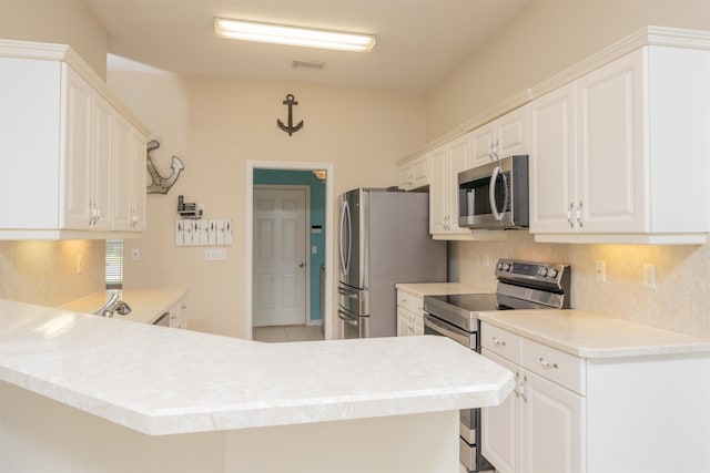 984 Windward Way, Saint Augustine, FL 32080 - kitchen with appliances with stainless steel finishes, backsplash, white cabinetry, light countertops, and a peninsula
