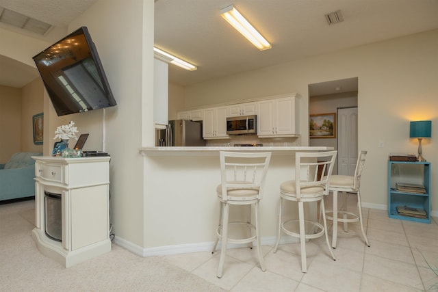 984 Windward Way, Saint Augustine, FL 32080 - kitchen with stainless steel appliances, a kitchen bar, white cabinets, a peninsula, and light countertops