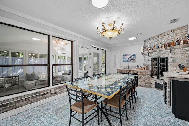 dining room with a fireplace, a textured ceiling, ornamental molding, and brick wall