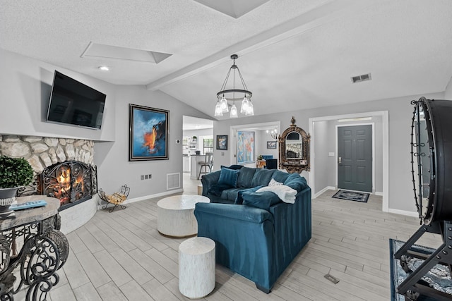 living room featuring a stone fireplace, vaulted ceiling with beams, a textured ceiling, a notable chandelier, and light hardwood / wood-style floors