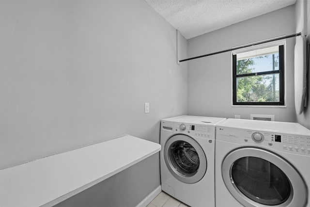 washroom with washer and clothes dryer, light tile patterned floors, and a textured ceiling