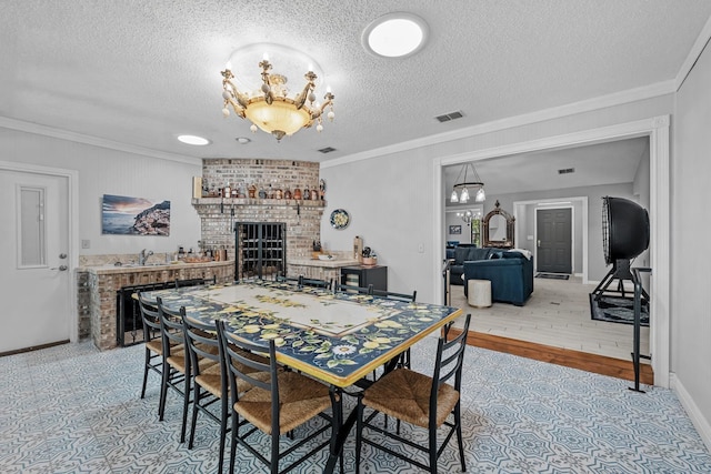 dining room with a fireplace, light hardwood / wood-style floors, a textured ceiling, and ornamental molding