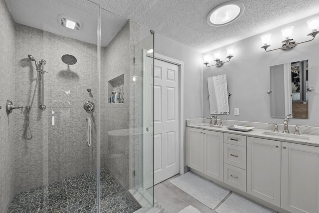 bathroom with vanity, a textured ceiling, tile patterned floors, and a shower with shower door