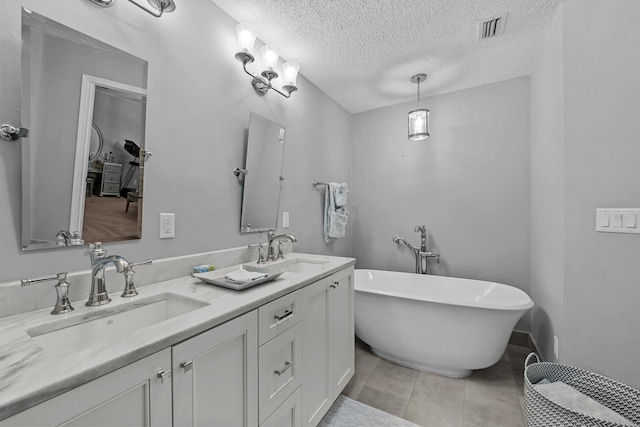 bathroom featuring tile patterned flooring, vanity, a textured ceiling, and a tub