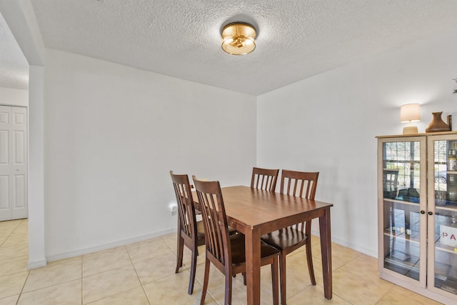 dining area with a textured ceiling, light tile patterned flooring, and baseboards