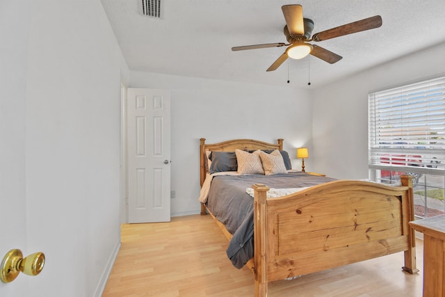 bedroom with baseboards, visible vents, ceiling fan, a textured ceiling, and light wood-type flooring