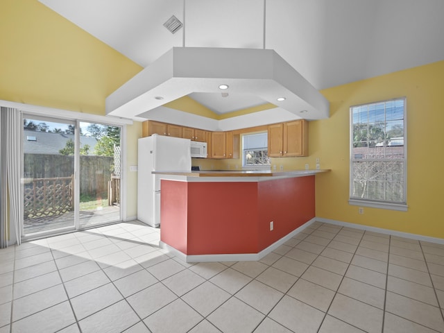 kitchen featuring light tile patterned floors, white appliances, plenty of natural light, and kitchen peninsula