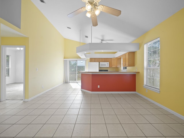 kitchen featuring light tile patterned floors, white appliances, a wealth of natural light, and kitchen peninsula