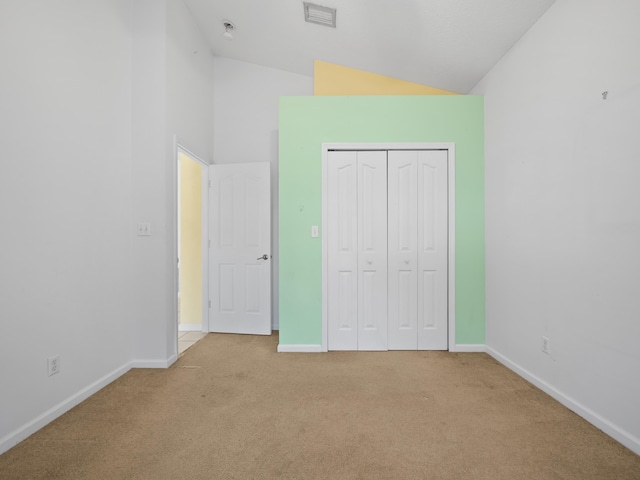 unfurnished bedroom with high vaulted ceiling, light colored carpet, and a closet