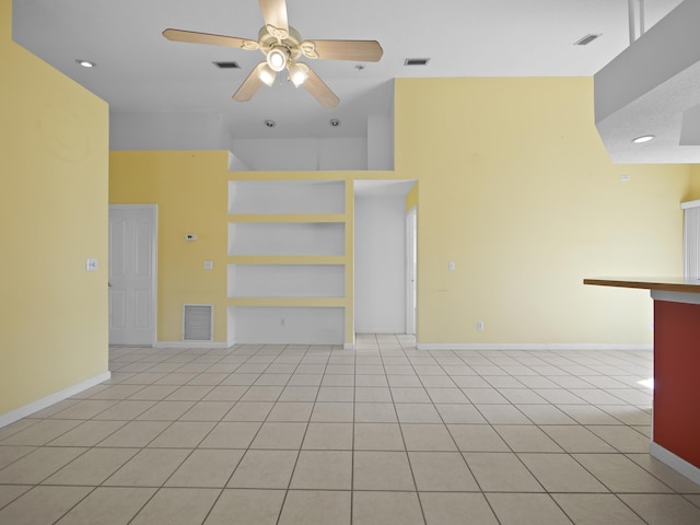 unfurnished living room with light tile patterned floors, built in shelves, and ceiling fan