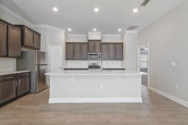 181 Narvarez Ave, Saint Augustine, FL 32084 - kitchen with stainless steel appliances, a center island with sink, dark brown cabinets, visible vents, and light countertops
