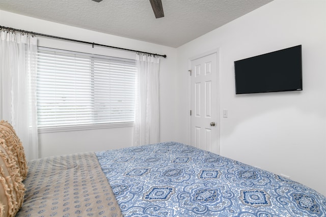 bedroom with ceiling fan and a textured ceiling