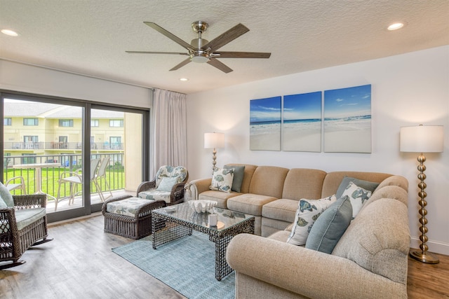 living room featuring hardwood / wood-style flooring, ceiling fan, and a textured ceiling