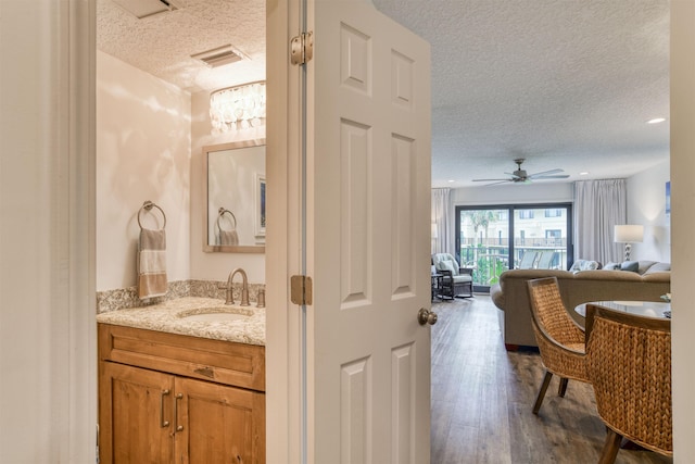 bathroom with vanity, hardwood / wood-style floors, a textured ceiling, and ceiling fan