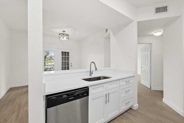 kitchen with light wood-type flooring, white cabinetry, stainless steel dishwasher, and sink