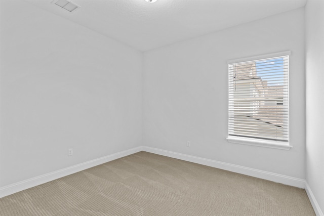 carpeted empty room featuring visible vents and baseboards