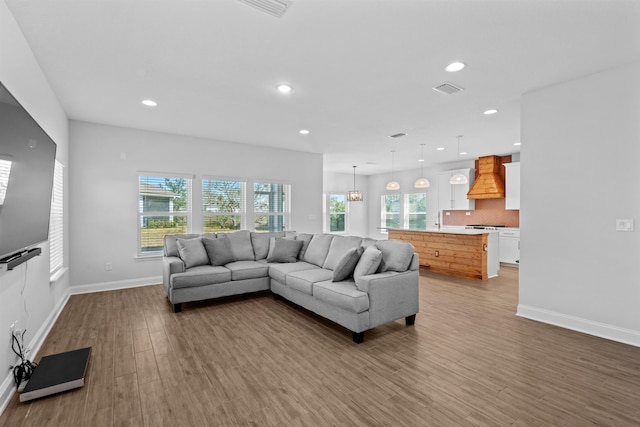 living room with baseboards, wood finished floors, visible vents, and recessed lighting