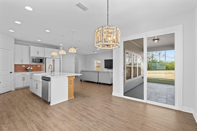 kitchen with open floor plan, stainless steel appliances, visible vents, and white cabinetry