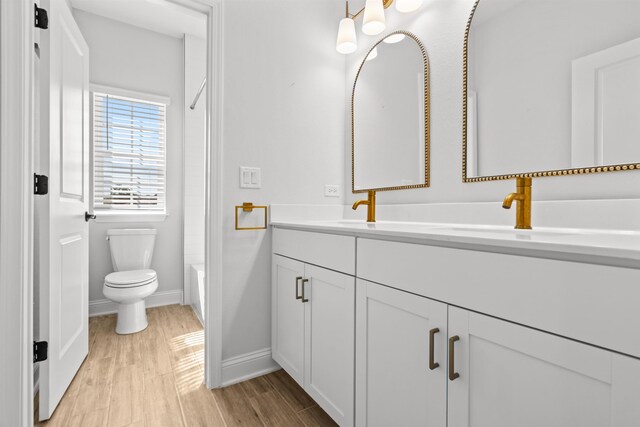 full bathroom with toilet, double vanity, baseboards, and a sink