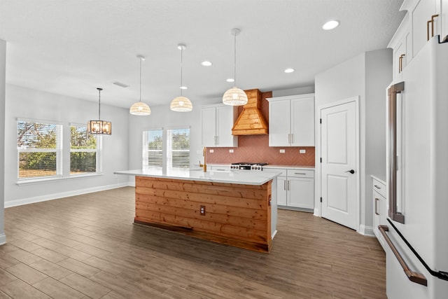 kitchen featuring tasteful backsplash, dark wood finished floors, custom exhaust hood, light countertops, and high end fridge