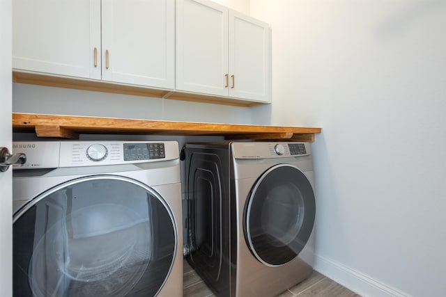 laundry room with washing machine and clothes dryer, cabinet space, and baseboards