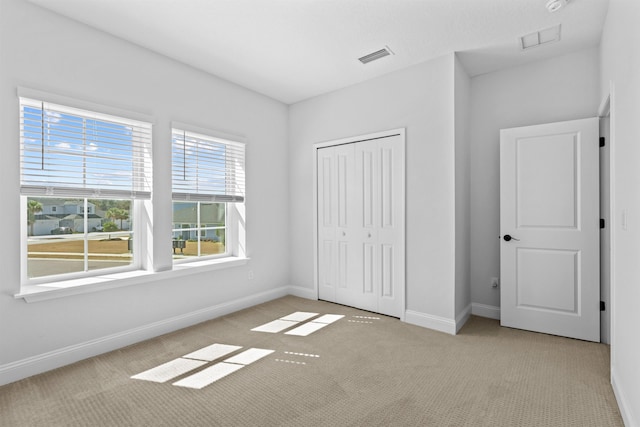 unfurnished bedroom featuring carpet floors, a closet, visible vents, and baseboards