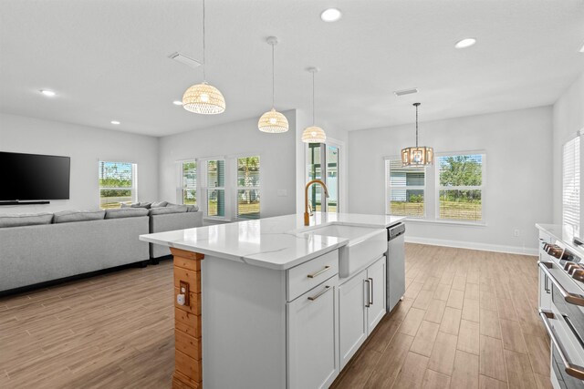 kitchen with recessed lighting, stainless steel dishwasher, white cabinetry, light wood-type flooring, and range