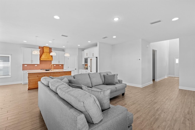 living area featuring baseboards, recessed lighting, visible vents, and light wood-style floors