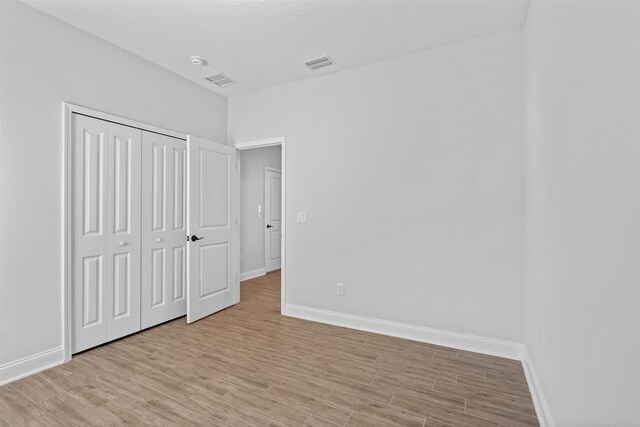 unfurnished bedroom featuring light wood-style floors, baseboards, and visible vents